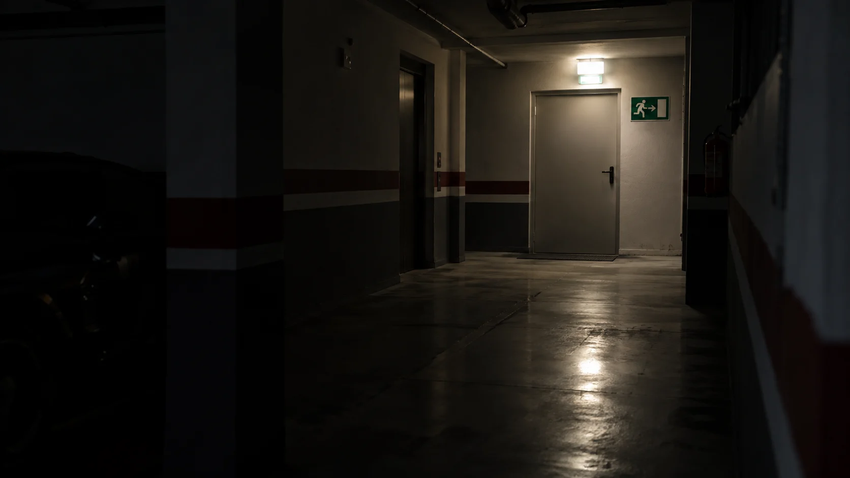 Luminaria de emergencia encendida sobre una puerta de salida en un pasillo